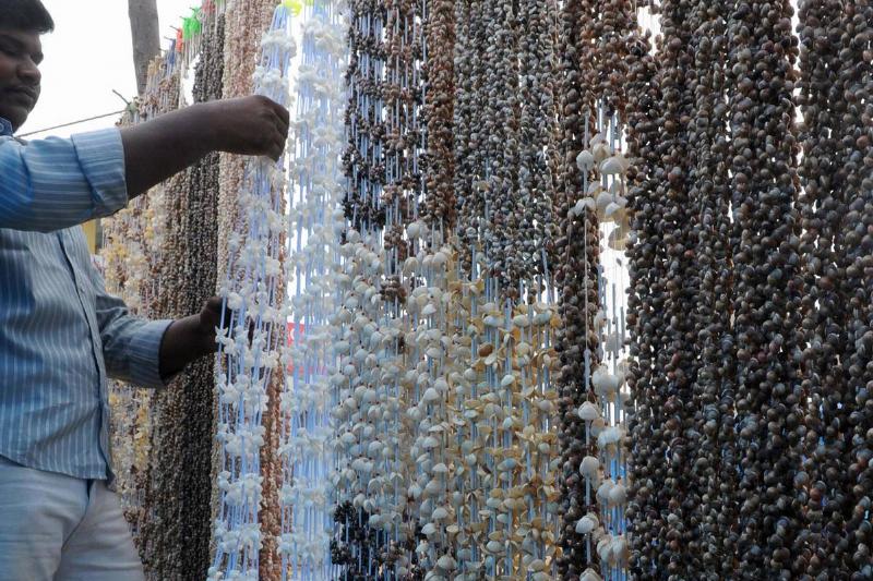 An Indian vendor arranges sea shell garl