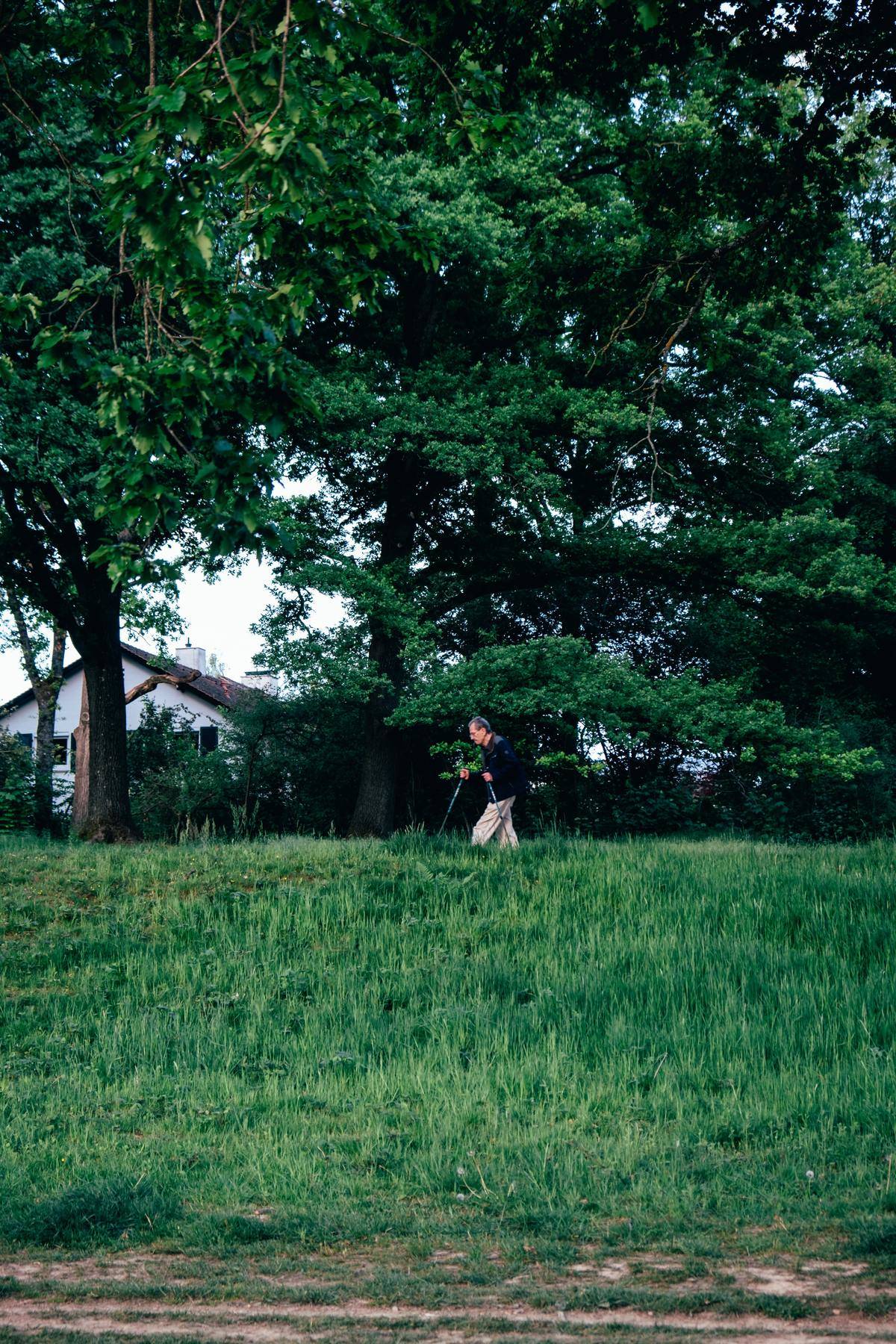 Man using walking sticks to cross a grassy expanse