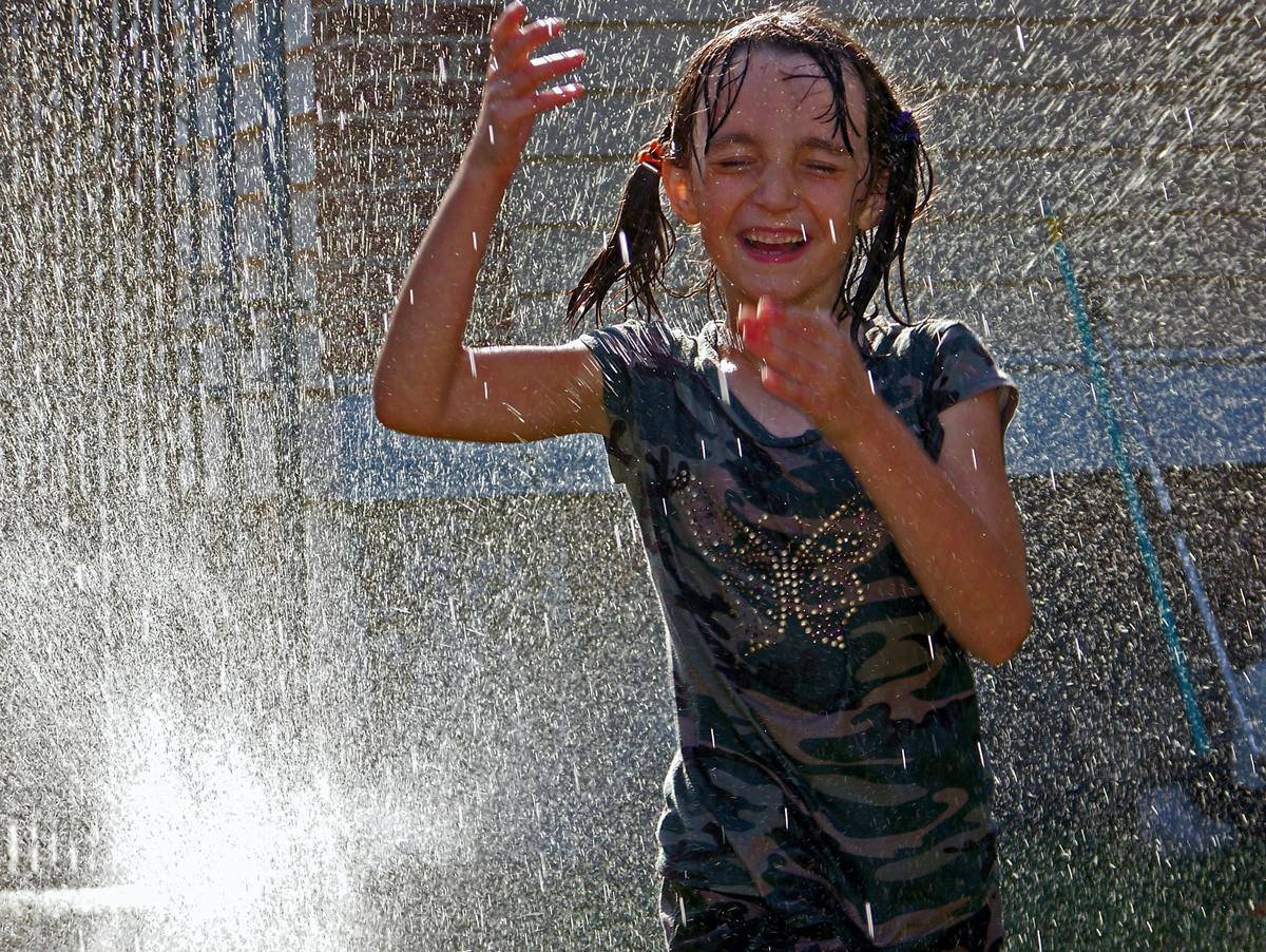 Young girl playing in a sprinkler