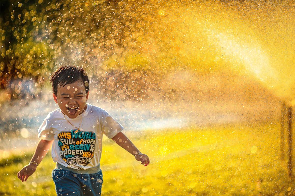 Young boy running through a sprinkler