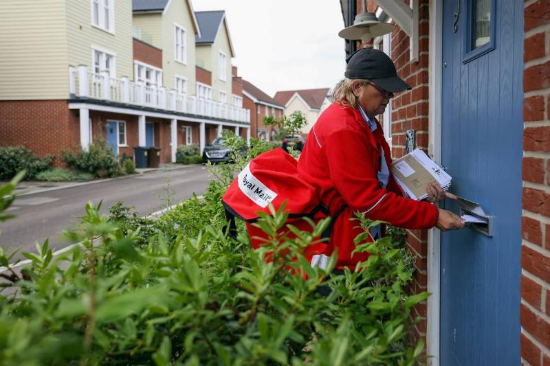 A post woman for Royal Mail Plc pushes post through a letterbox in Chelmsford, U.K., on Thursday, May 13, 2021.