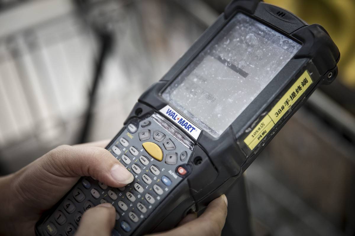 An employee holds a scanning device inside a Wal-Mart Stores Inc.'s Sam's Club store in Shenzhen, China,