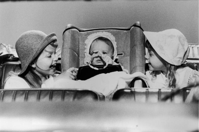 L-R: Actor Candace Cameron (L) and Jodie Sweetin smile at a baby (played by either Mary-Kate or Ashley Olsen) in a still from the television series, 'Full House,' circa 1987. 