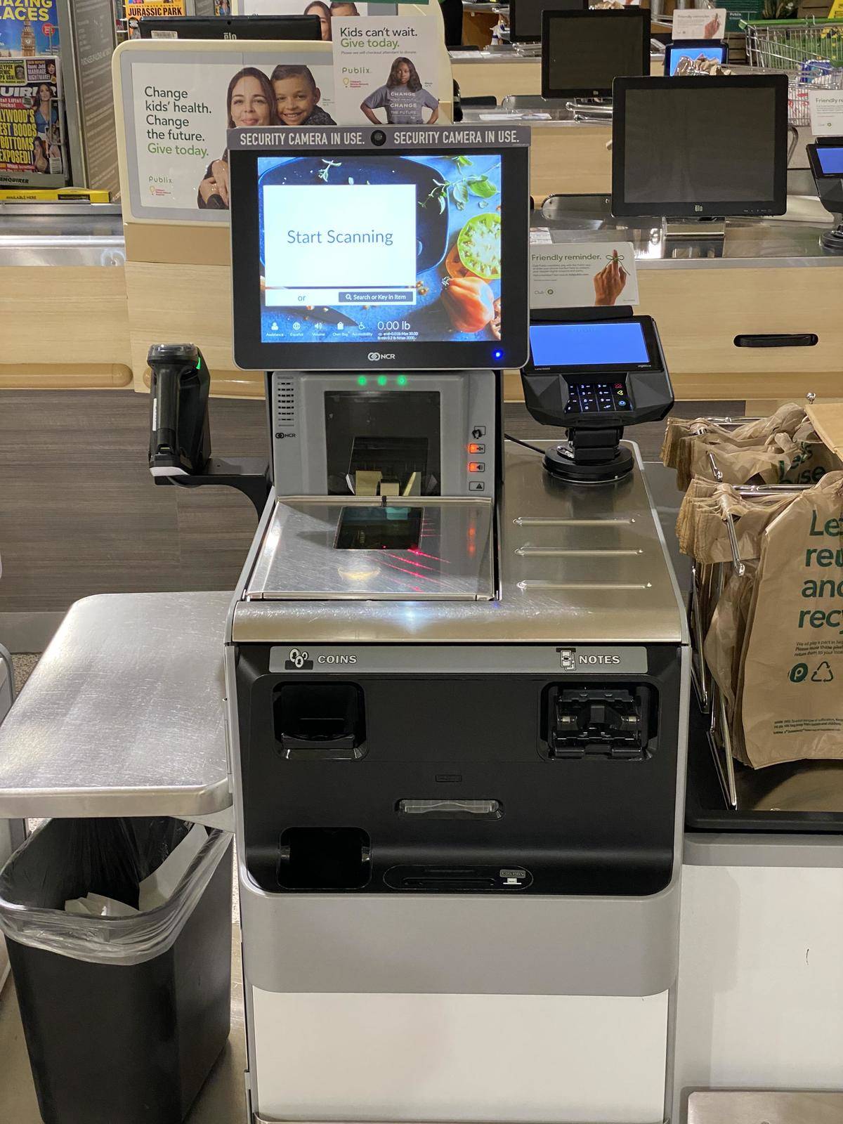 self checkout machine with a sticker saying a camera is watching