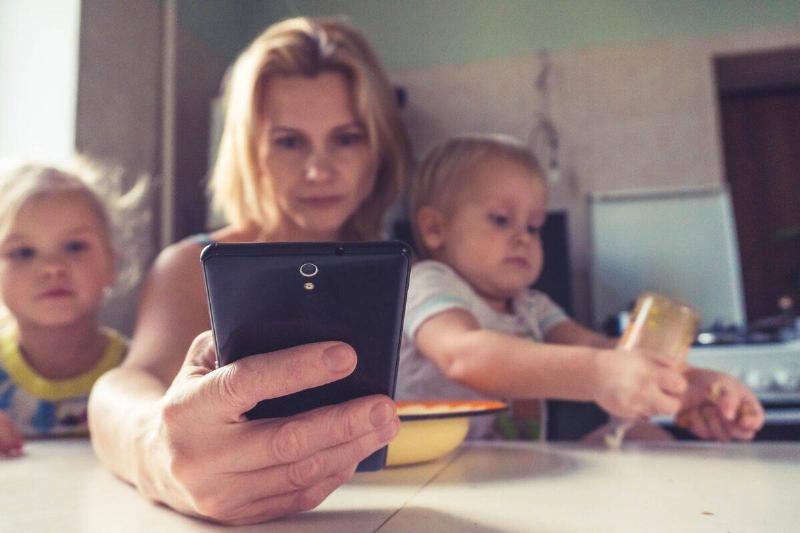 Woman on phone next to two children