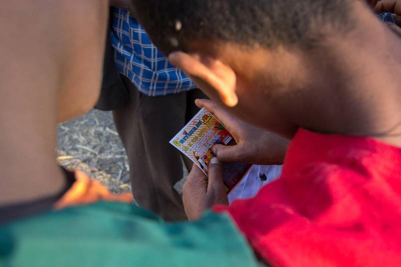 Ethiopian child playing a scratch-off lottery, Amhara region, Lalibela, Ethiopia