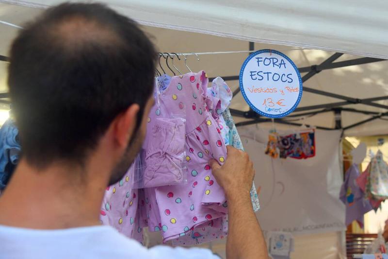 A man browses discounted baby clothes at a Clearance sale...