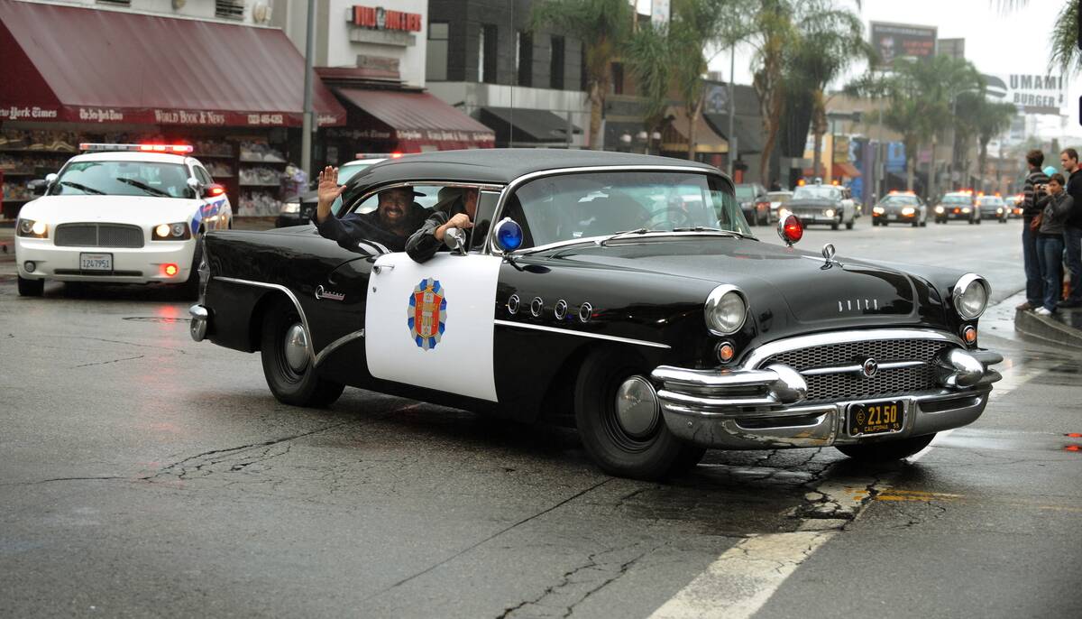 A 1950's eras Buick police car leads a p