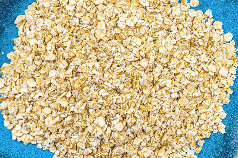 In this photo illustration, a pile of raw oatmeal on a blue...