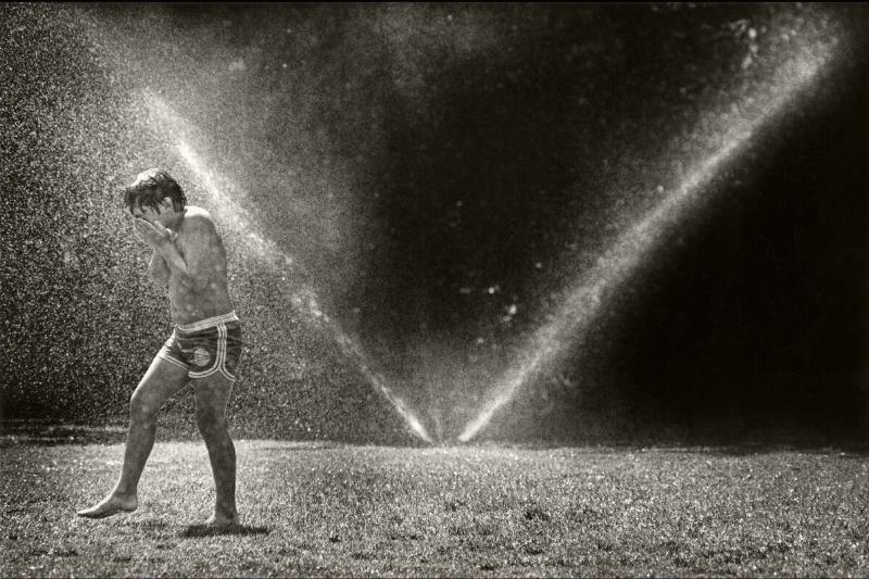 Boy Plays In A Sprinkler