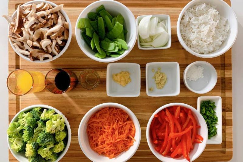Overhead view of pre-prepped ingredients placed in bowls, which are sat on a wooden cutting board
