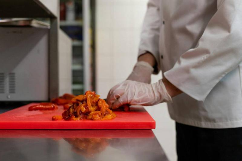Chef cutting food on a plastic red cutting board