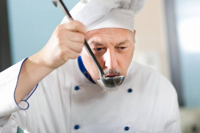 Chef sipping liquid from a ladle