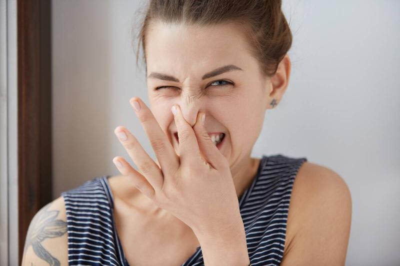 Woman plugging her nose with her fingers