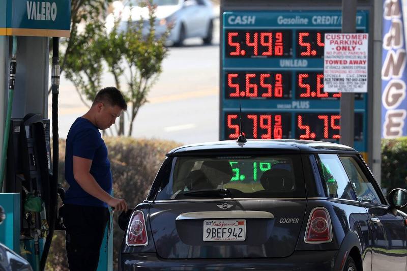 Man filling up his blue Mini Cooper at a gas station