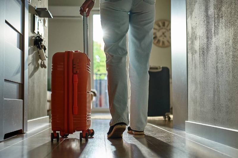 Person rolling a suitcase toward his front door