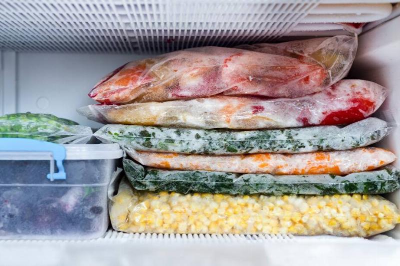 Bags and containers of frozen vegetables in a freezer