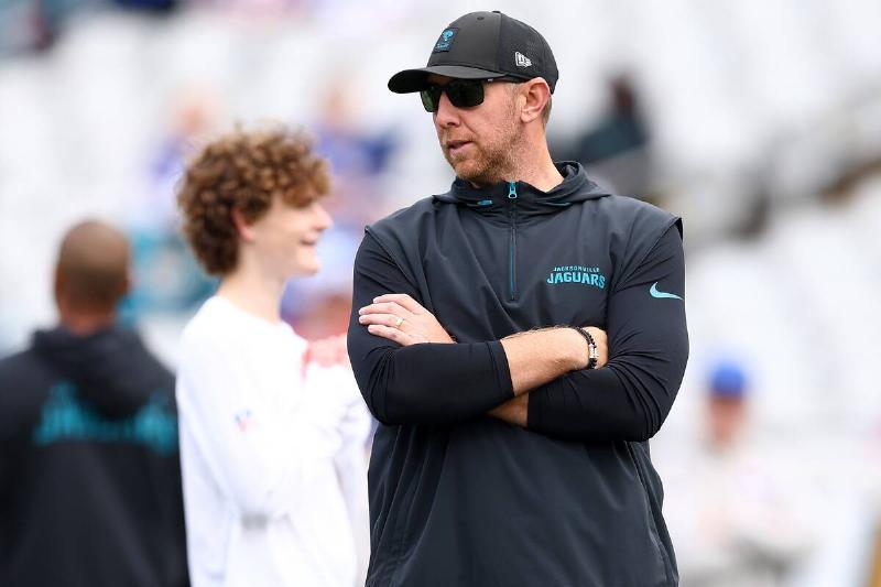 Liam Coen standing in front of a man and another Jacksonville Jaguars employee