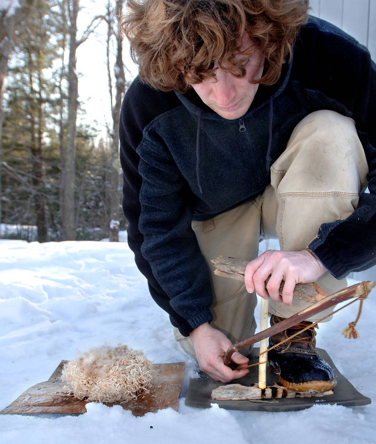 Man starting a fire in the snow a primitive way