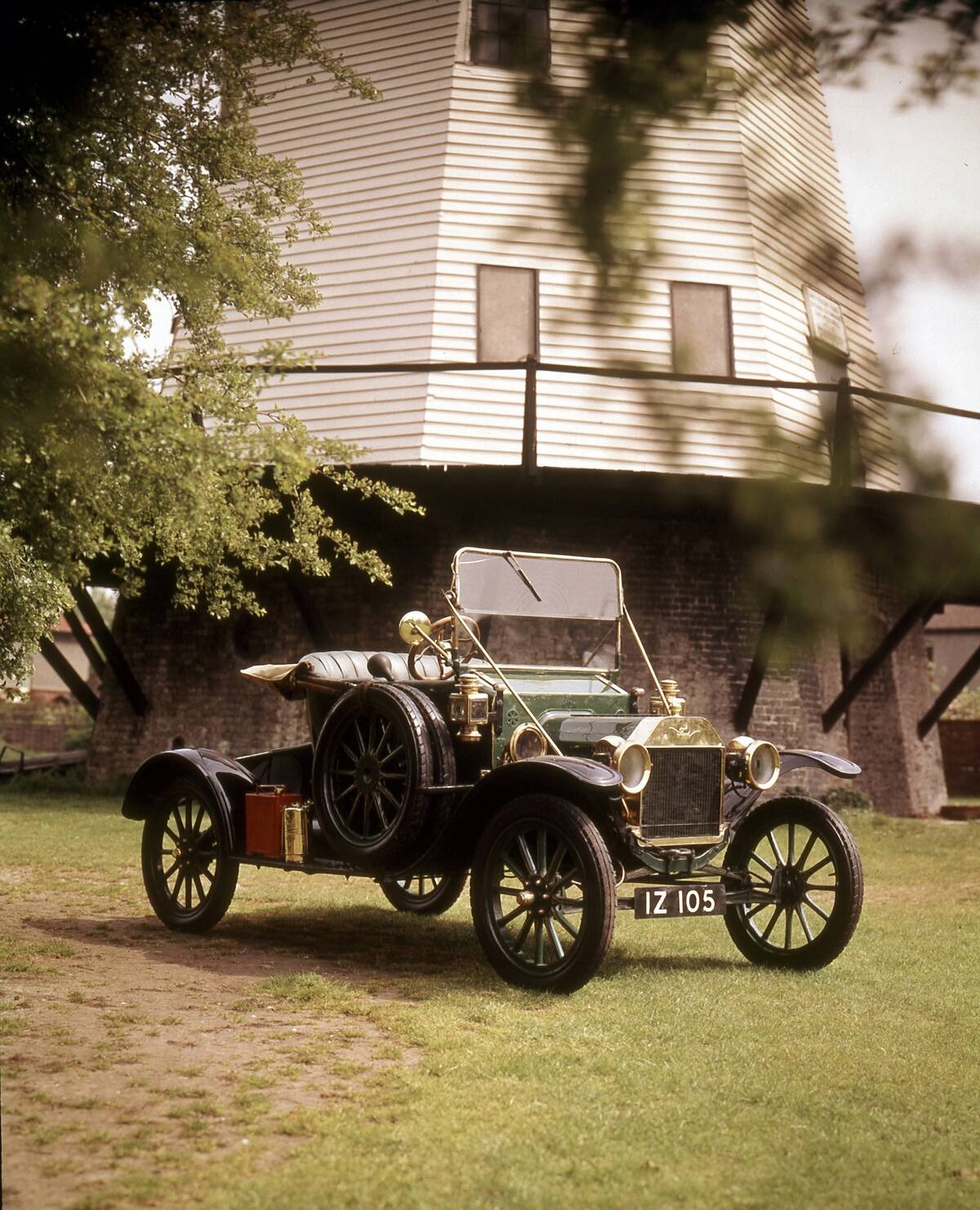 Ford Model T parked in grass, next to a building