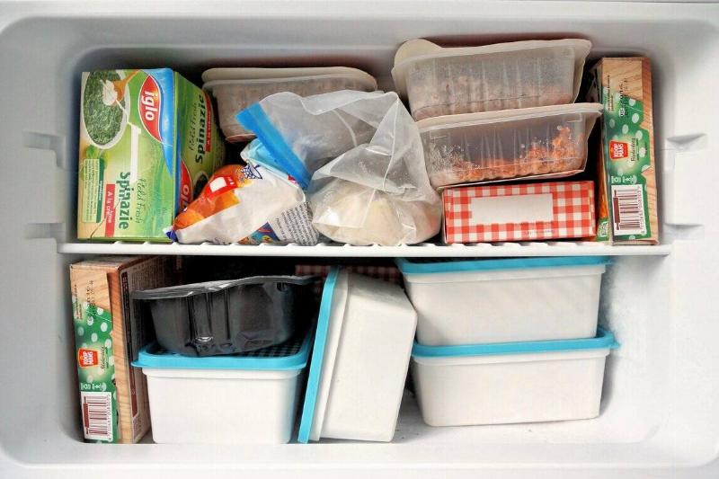 Freezer filled with containers, bags and boxes of frozen food