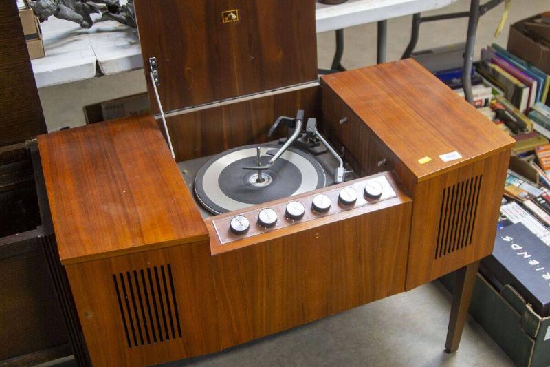HMV record player wooden cabinet next to various items on the ground and atop a table
