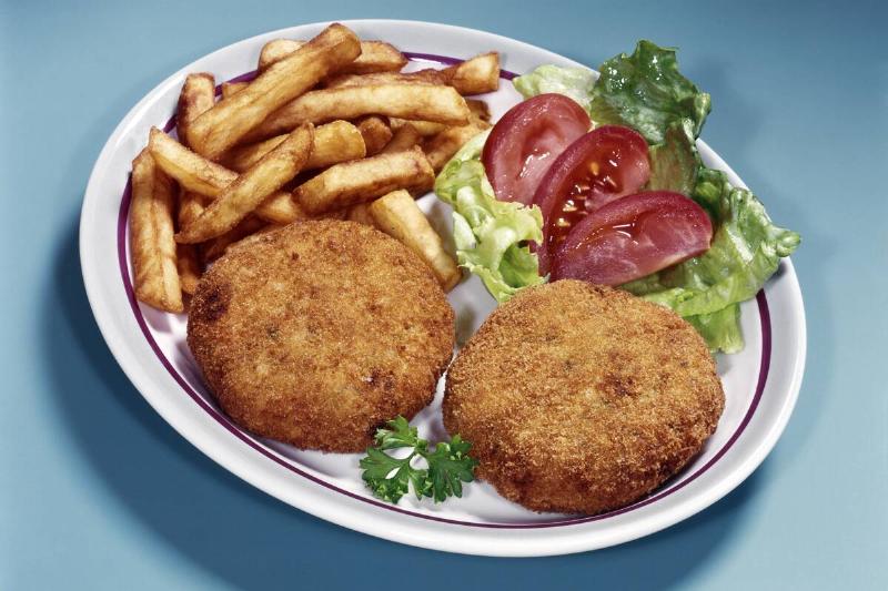 Crab cakes, fries, lettuce and sliced tomatoes on a plate