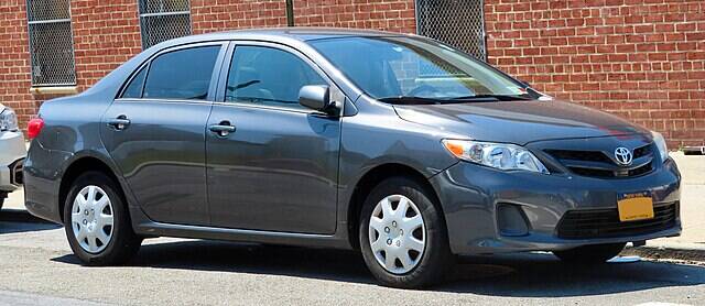 Grey 2012 Toyota Corolla parked beside a brick building