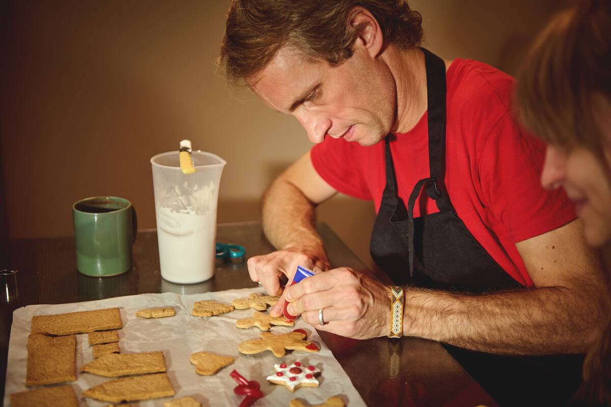 Woman watching a man ice cookies at a wooden table