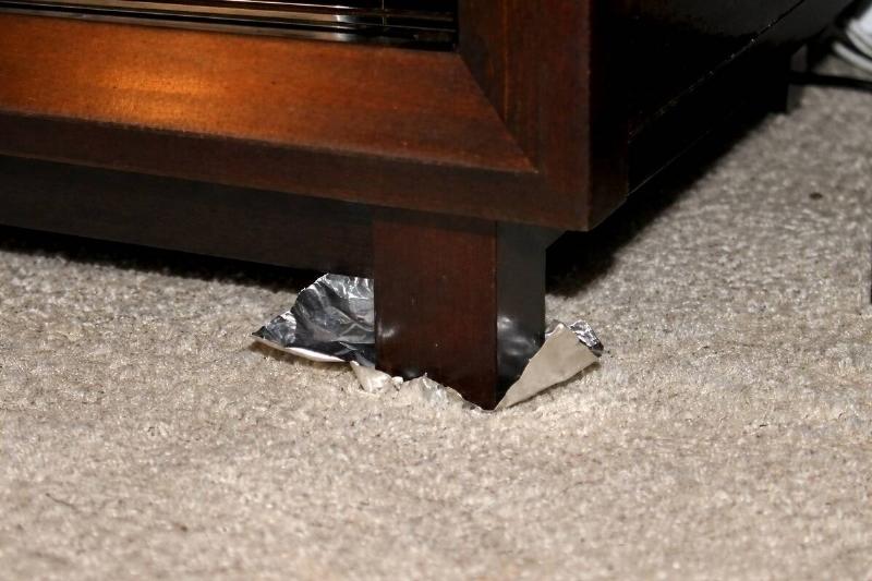 AI rendering of a piece of aluminum foil wedged between a carpeted floor and a furniture leg
