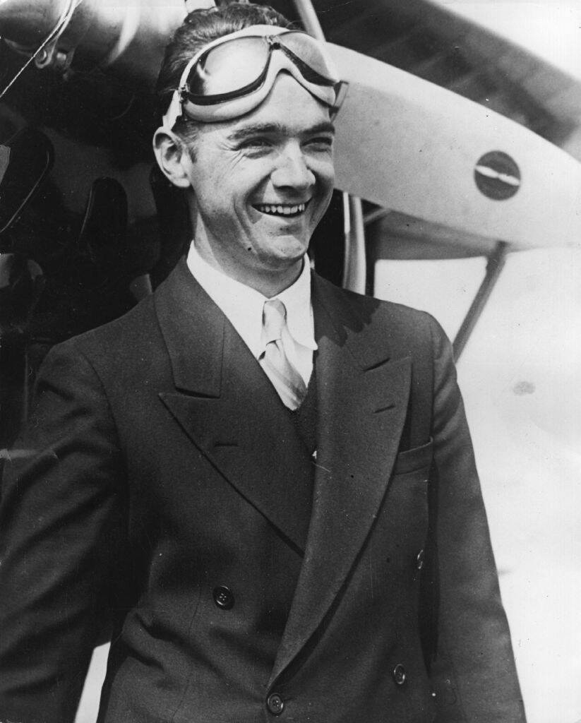 Howard Hughes standing next to an aircraft