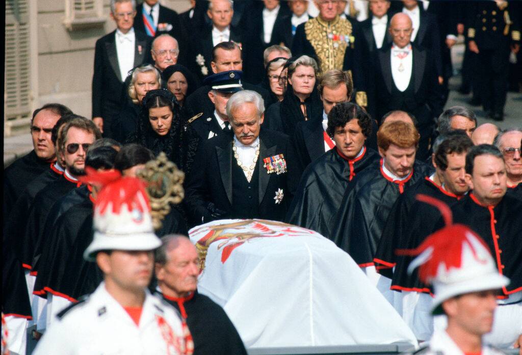 Mourners gathered around a coffin draped with a flag
