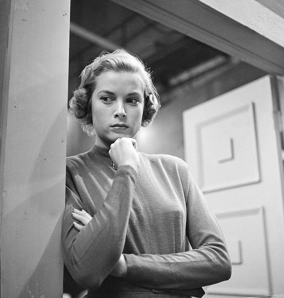 Grace Kelly standing in a doorway, with her chin resting on her fist