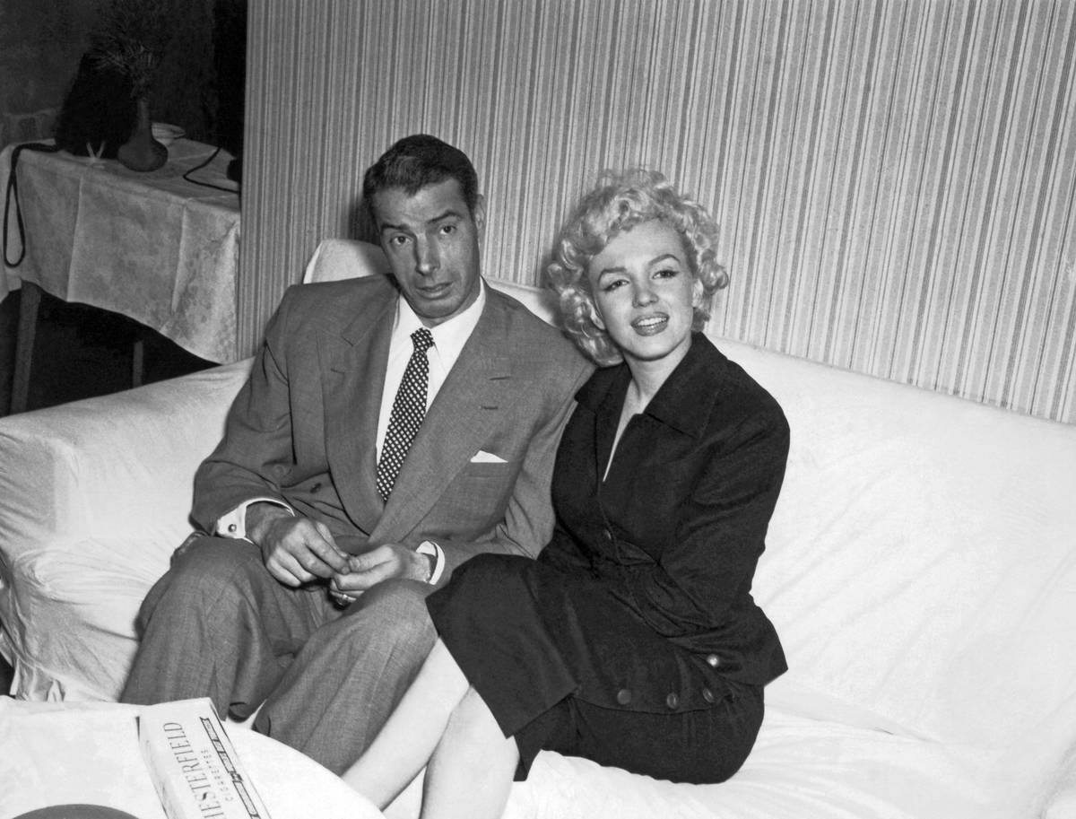 Marilyn Monroe and Joe DiMaggio sitting on a couch