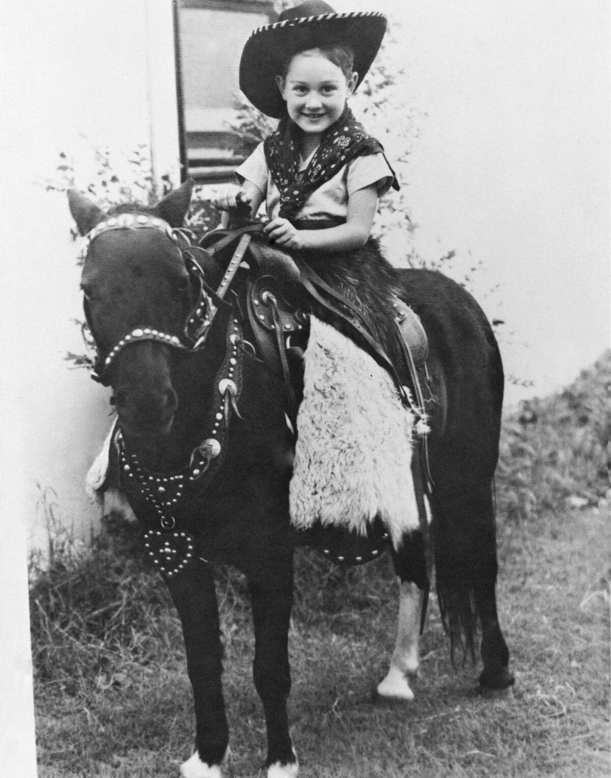 A young Buddy Holly, dressed as a cowboy, sitting on the back of a pony