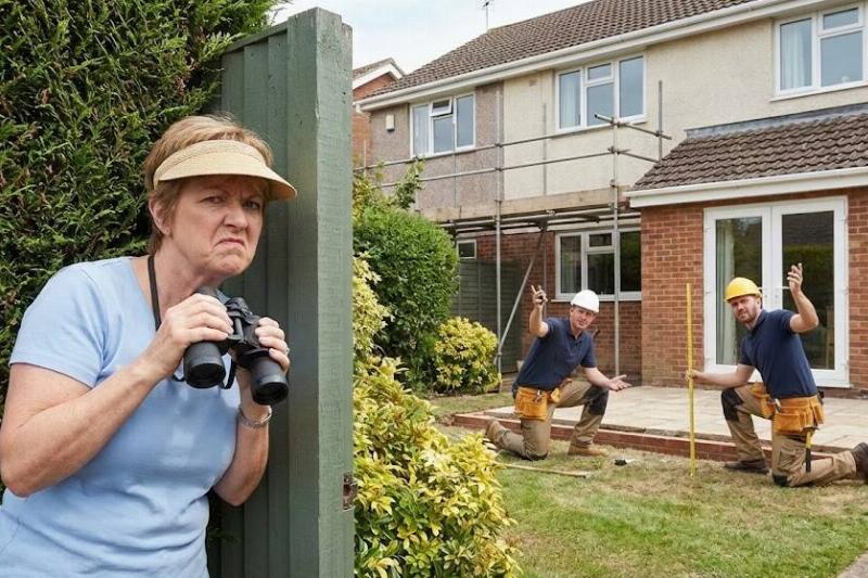Woman standing behind a fence, holding binoculars. Two construction workers are working on a deck at the back of her house
