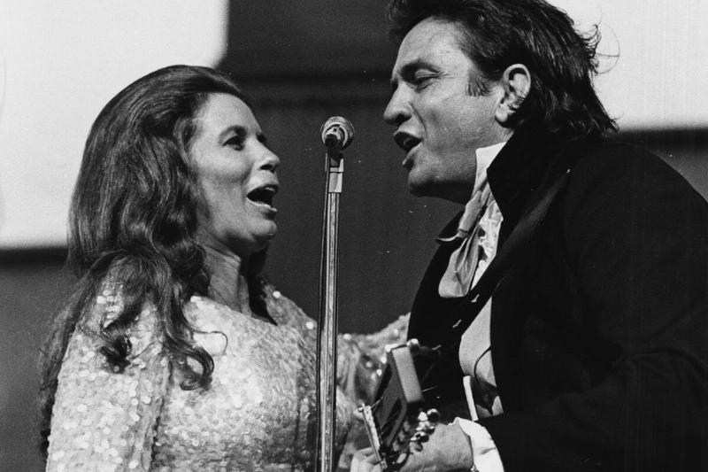June Carter and Johhny Cash singing together at a microphone