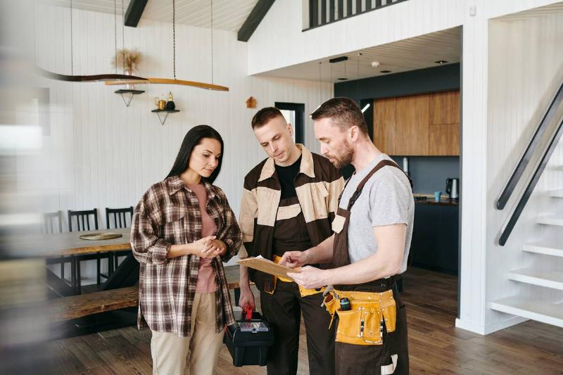 Man and woman standing with a contractor in the middle of a dining area
