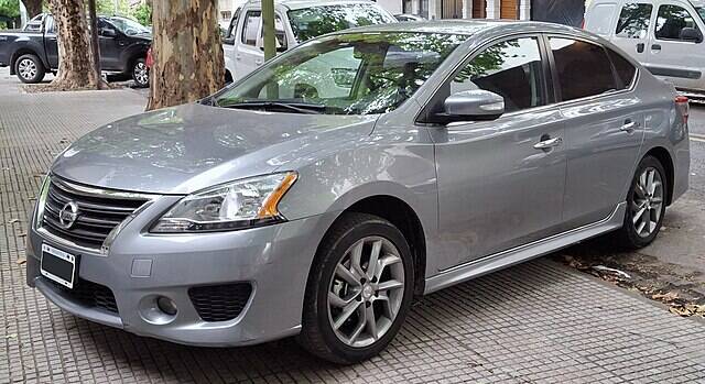 Silver 2014 Nissan Sentra parked on the sidewalk, near a tree