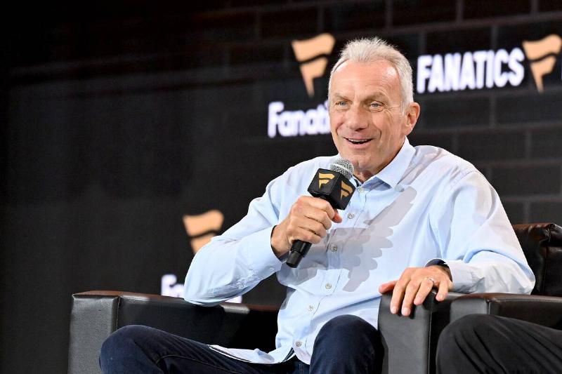 Joe Montana sitting in a sort chair, holding a microphone to his face