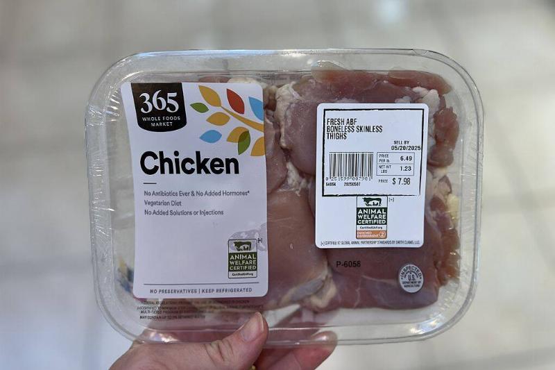 Person off-screen holding up a package of chicken thighs
