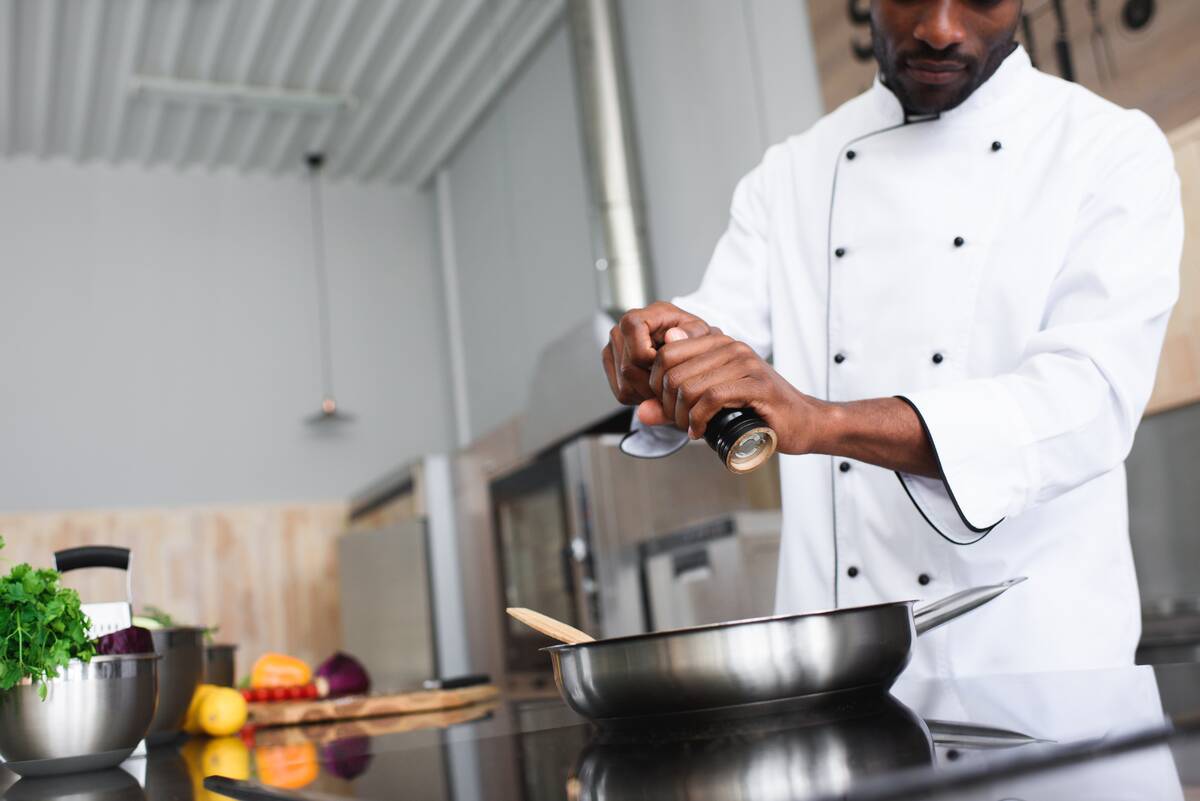 Chef seasoning food in a frying pan