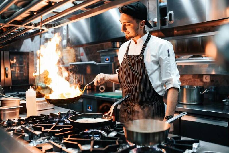 Chef holding a frying pan over a stovetop