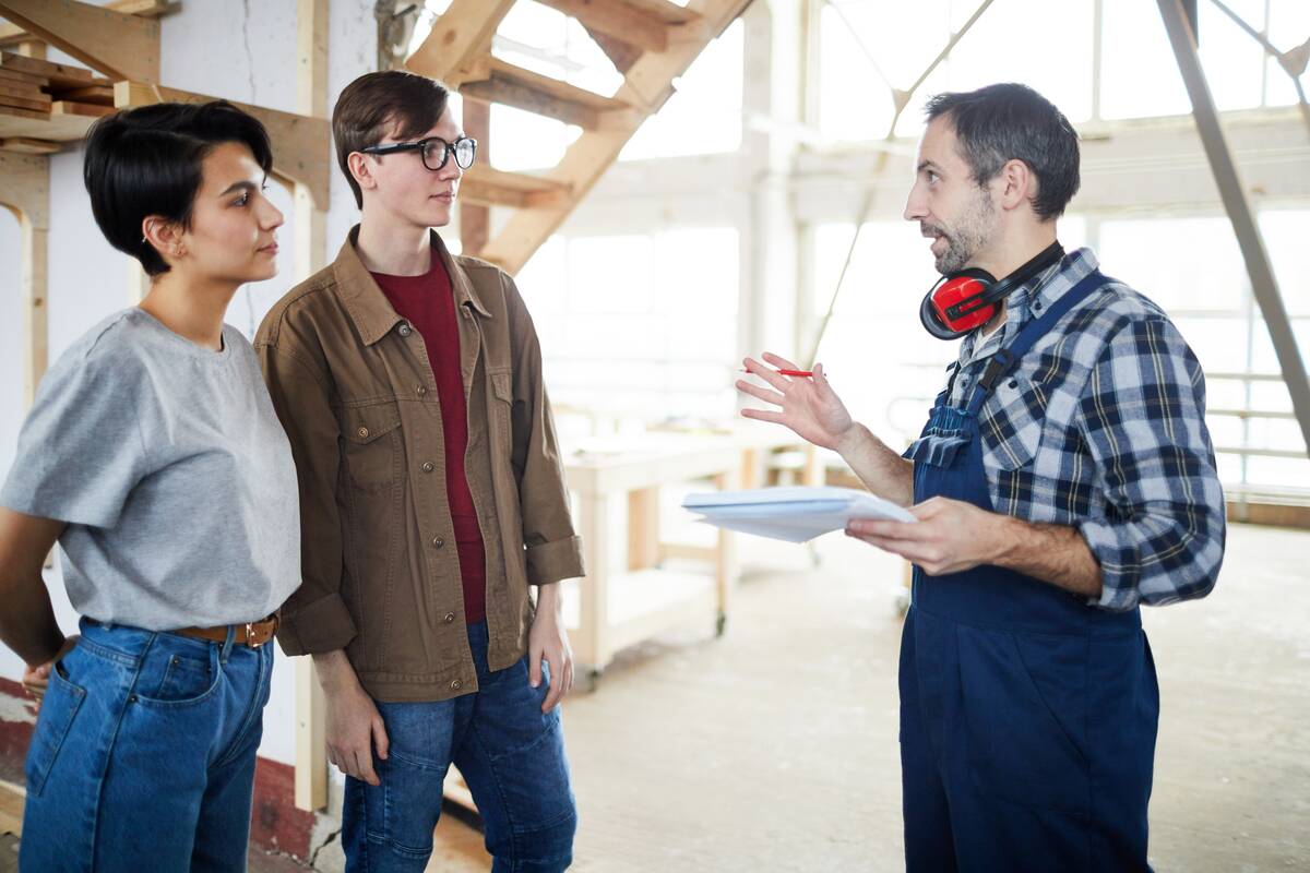 Construction worker speaking to a husband and wife in the middle of a construction site