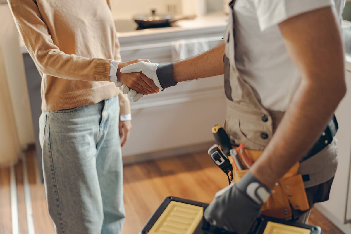 Woman shaking a repairman's hand in the middle of her kitchen