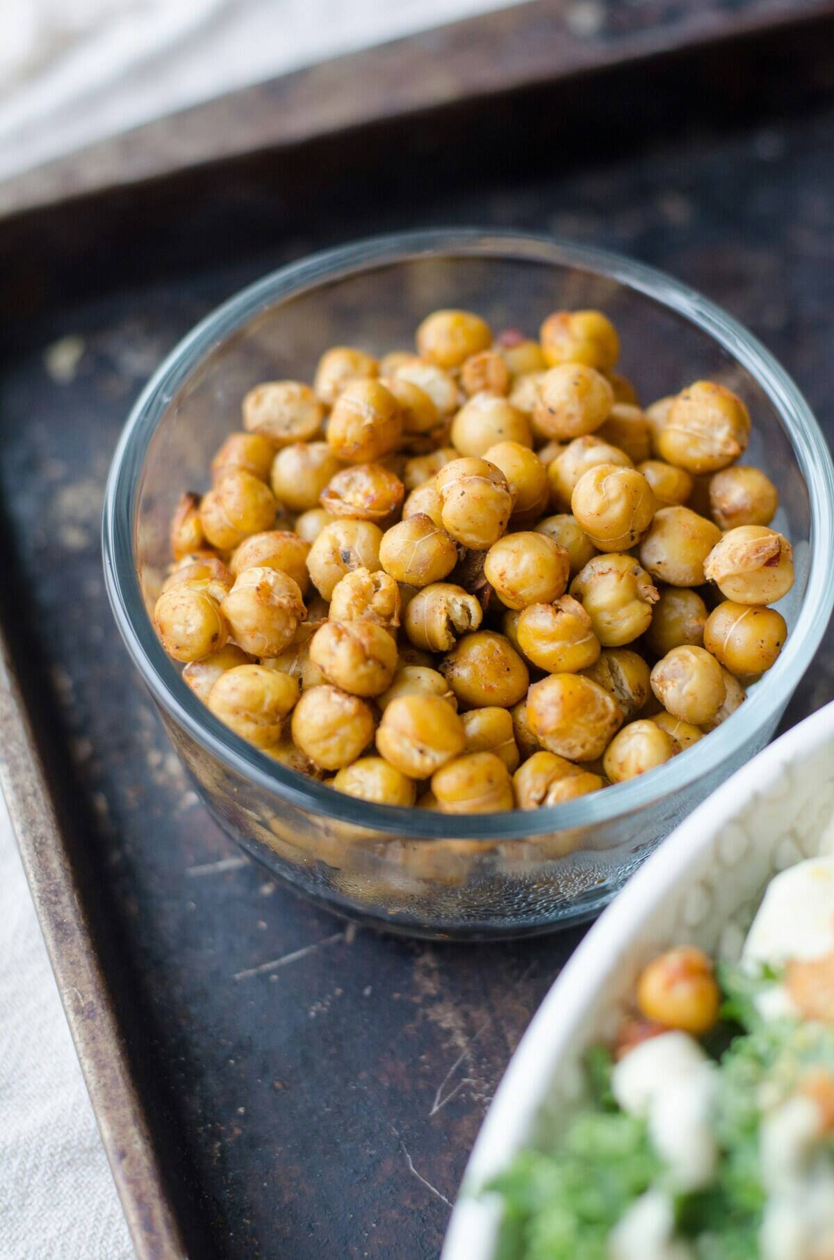 Roasted chickpeas in a glass bowl, placed next to a bowl that's slightly off-screen