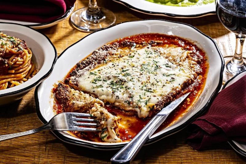 Shallow bowl of chicken parmesan, next to small bowl of spaghetti