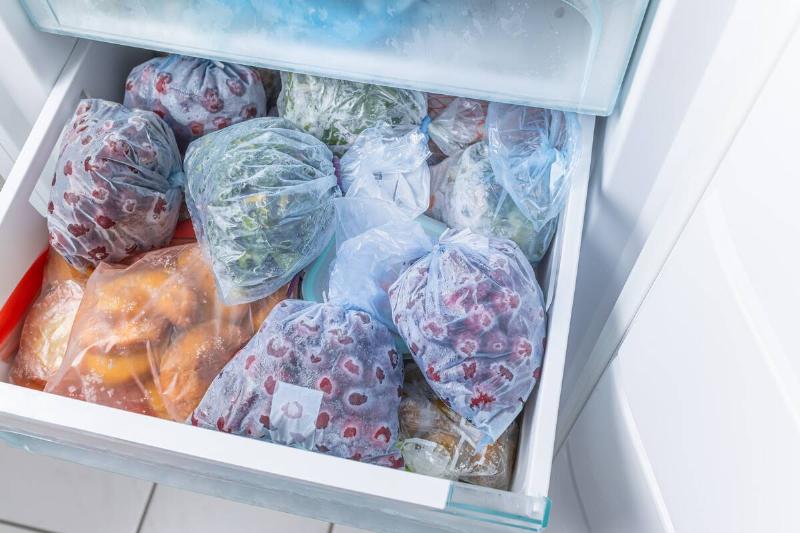 Bags of frozen fruit and vegetables in a freezer