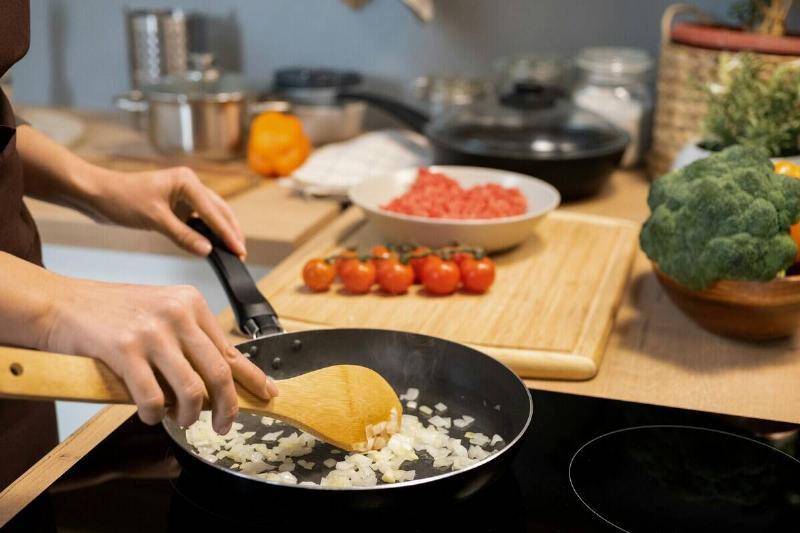 Person off-screen frying onions in a pan