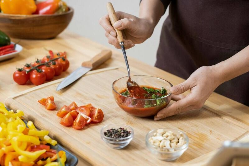 Person off-screen making sauce in a glass bowl